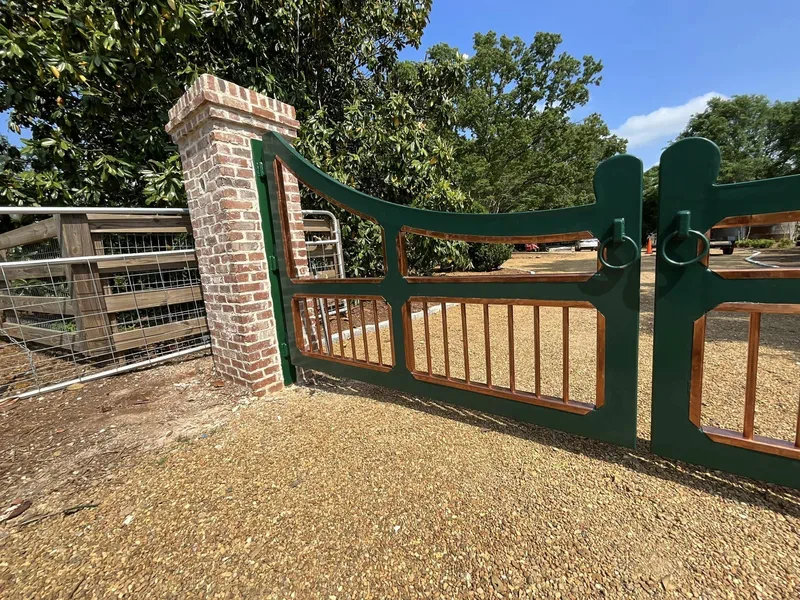 Green metal gate with a matching fence panel at a property entrance