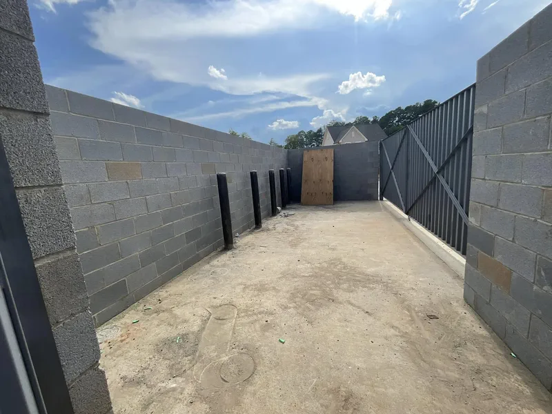 Metal gate and fencing enclosing a service corridor between block walls