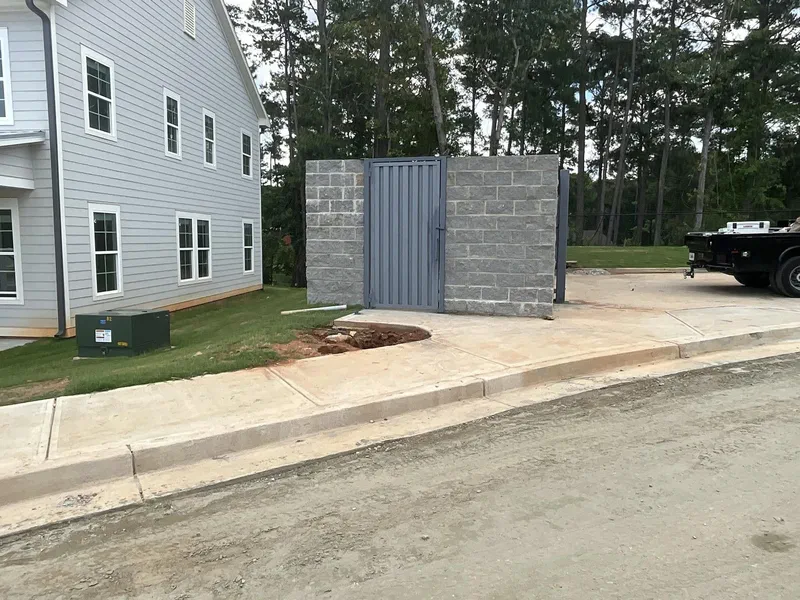 Metal dumpster enclosure gates set into a block wall