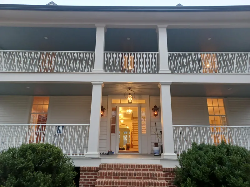 Two-storey porch fronted with decorative metal railings on a white house