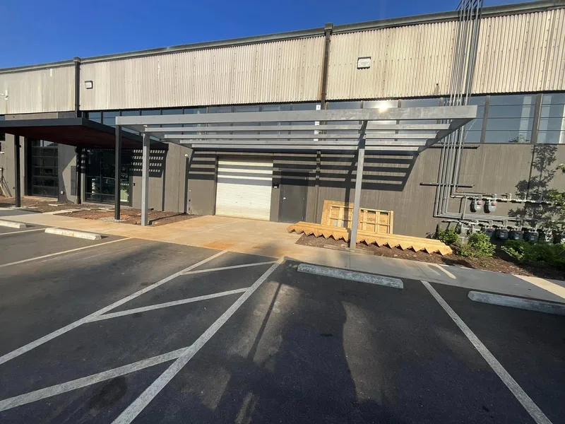 Steel canopy frame over a commercial entrance and parking bay