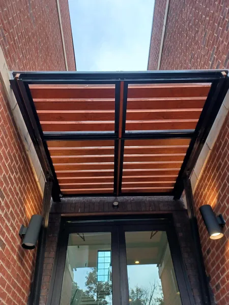 Steel and timber entrance canopy cantilevered off a brick building