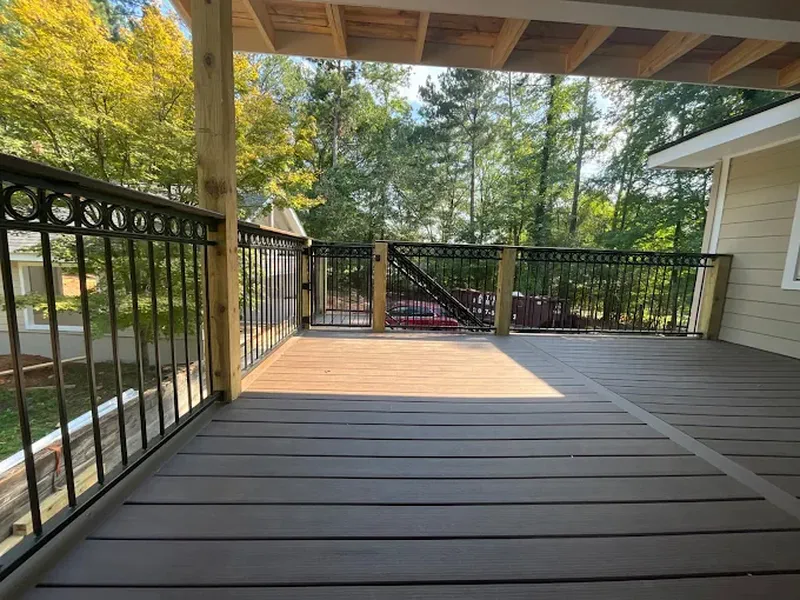 Composite deck edged with black metal balusters overlooking woodland