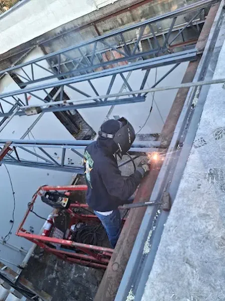 Welder on a lift joining steel framing at the edge of a building