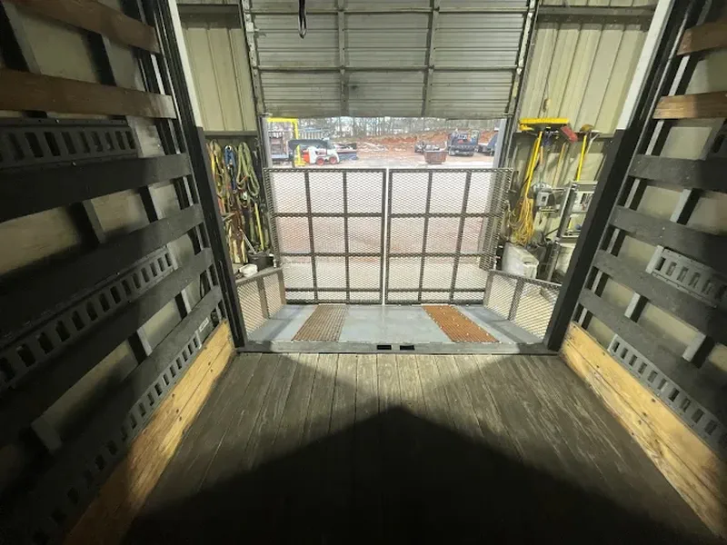 Inside an enclosed trailer showing steel wall framing and the open ramp