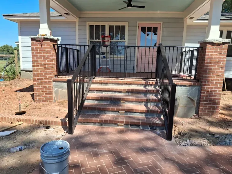 Black metal handrail on the brick front steps of a new house