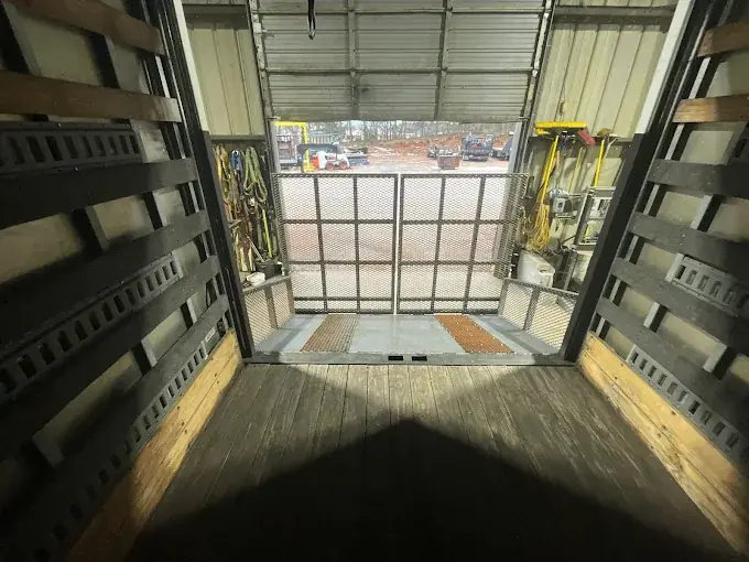 Inside an enclosed trailer showing steel wall framing and the ramp opening