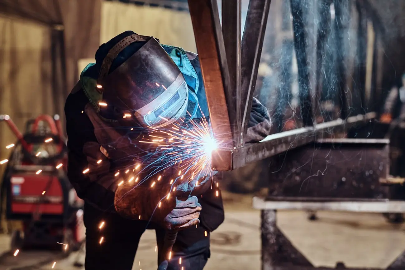 Welder striking an arc on structural steel with sparks scattering