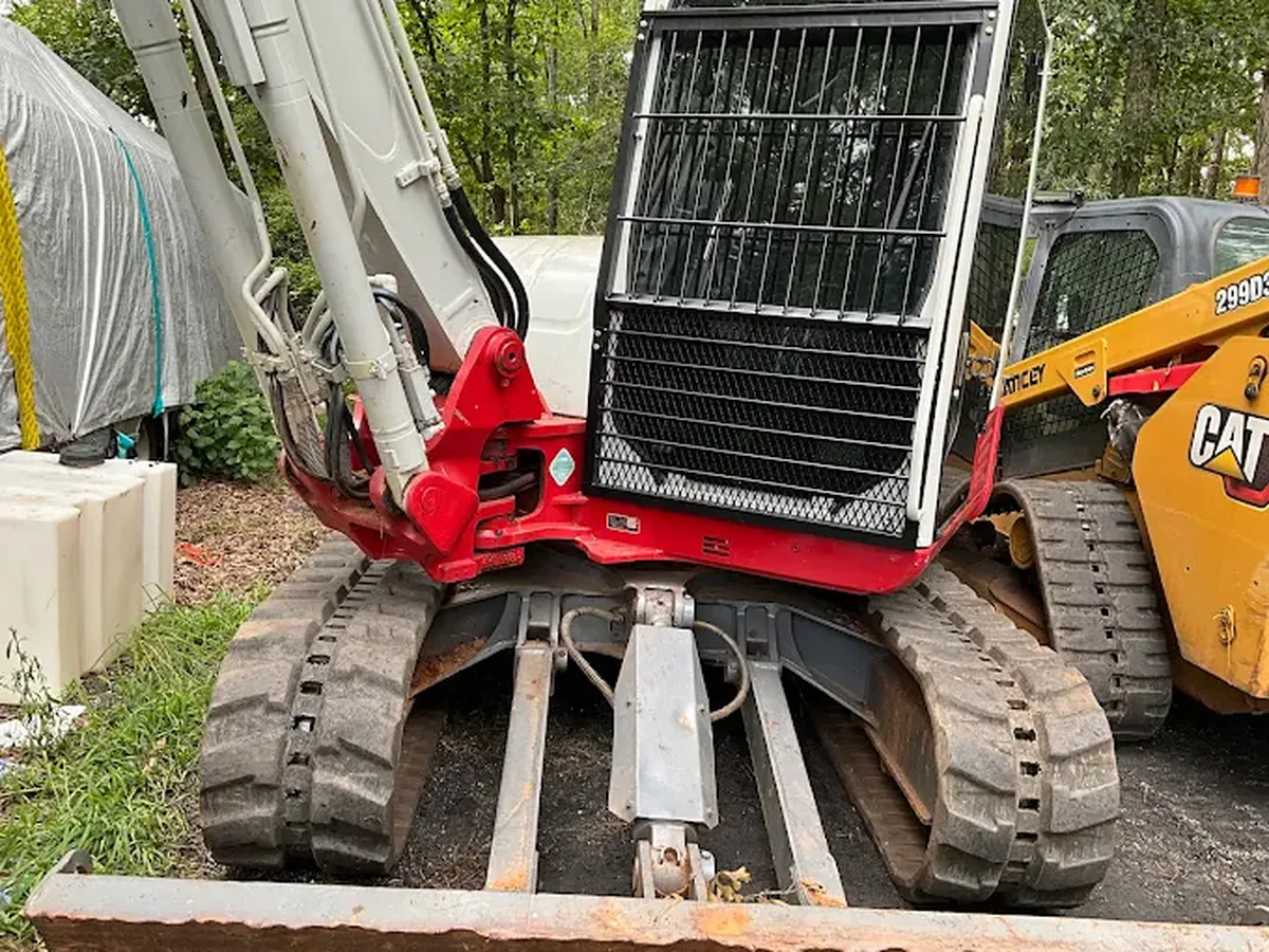Red grapple attachment fitted to an excavator arm on site