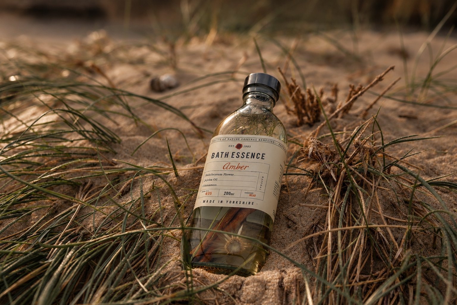 A bottle of Amber bath essence resting in the dune grass