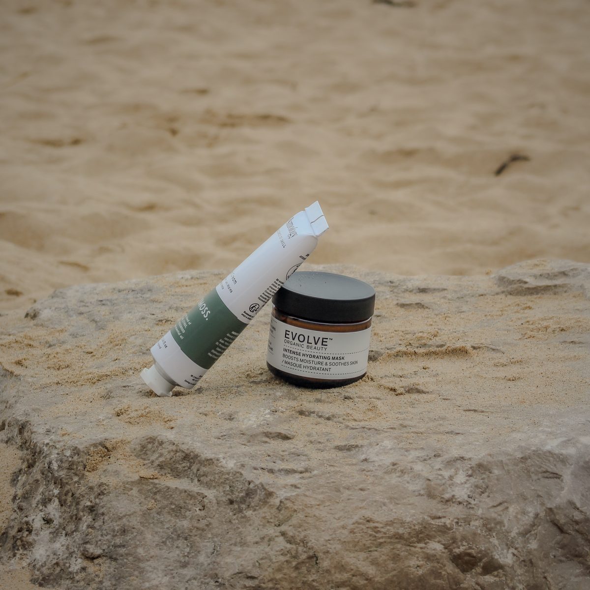 Hand cream and hydrating mask on a sea-worn rock