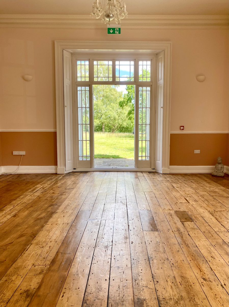 A light-filled room at The Retreat New Forest with tall garden doors open onto the lawn