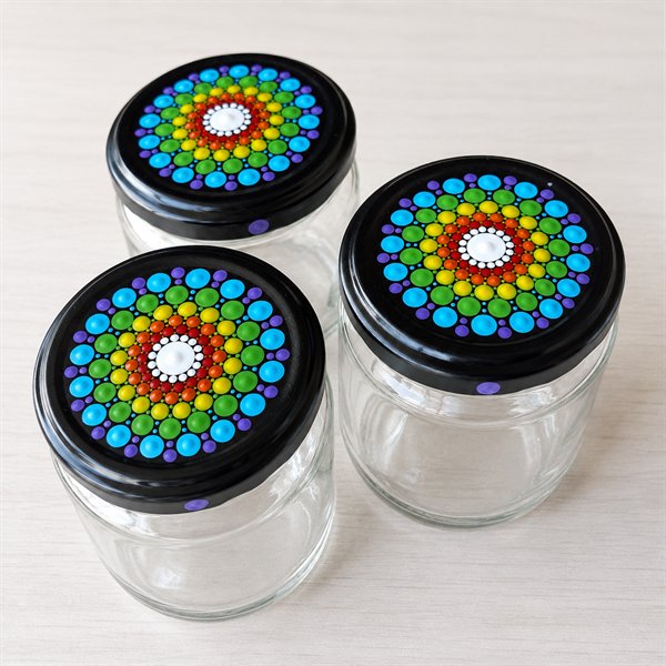 Tres frascos de vidrio con la tapa pintada en puntillismo, mandalas de colores sobre negro