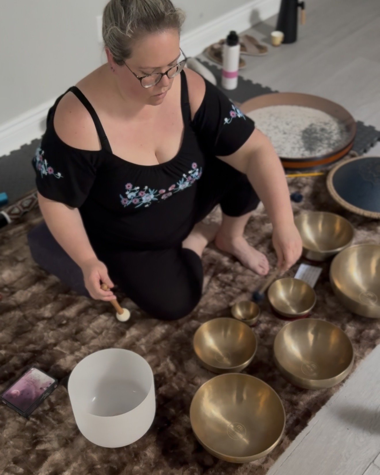 Karolina Autumn playing the crystal bowl and striking a tibetan bowl