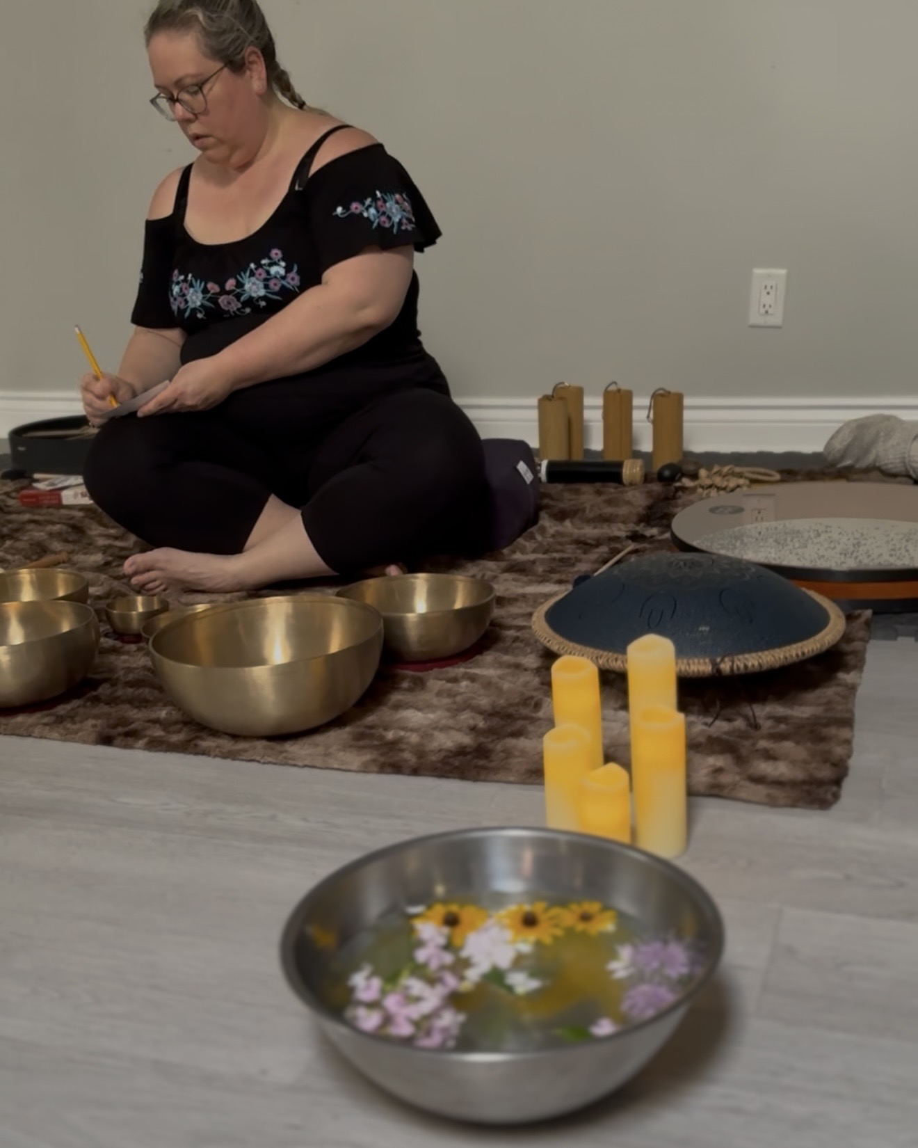 Karolina Autumn sitting amongst sound healing instruments writing on a piece of paper
