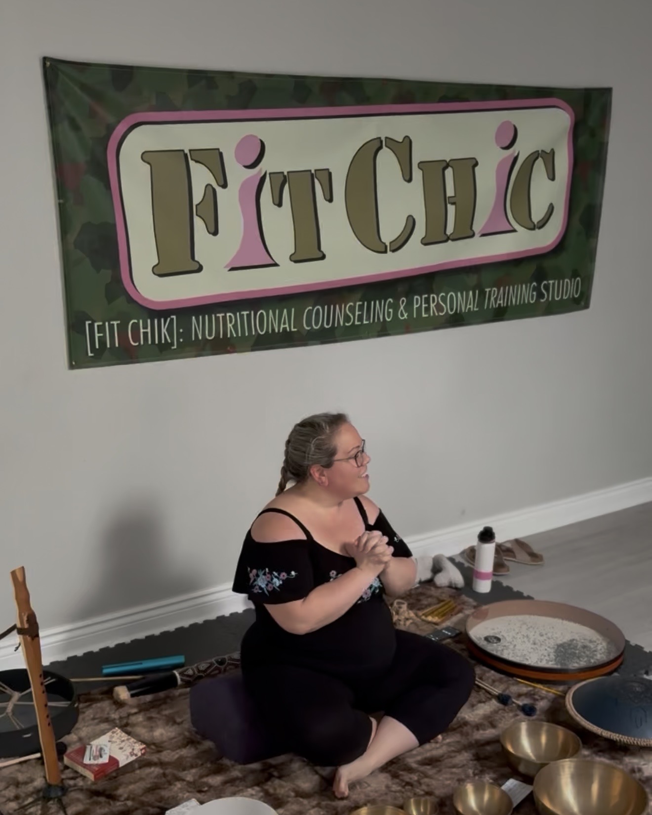 Karolina Autumn sitting beneath a sign for FitChic Infinity