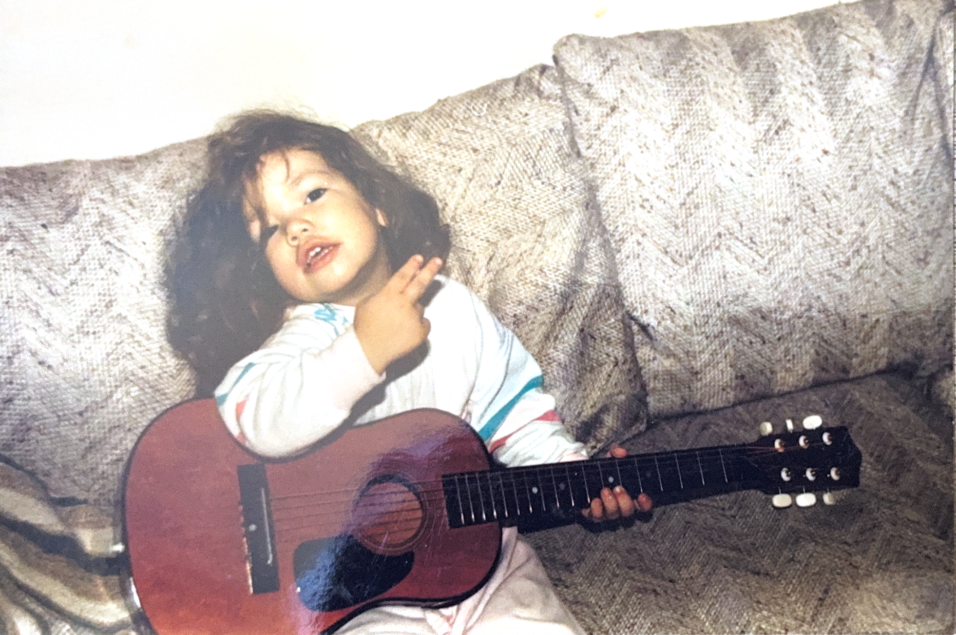 Karolina as a child sitting with a guitar