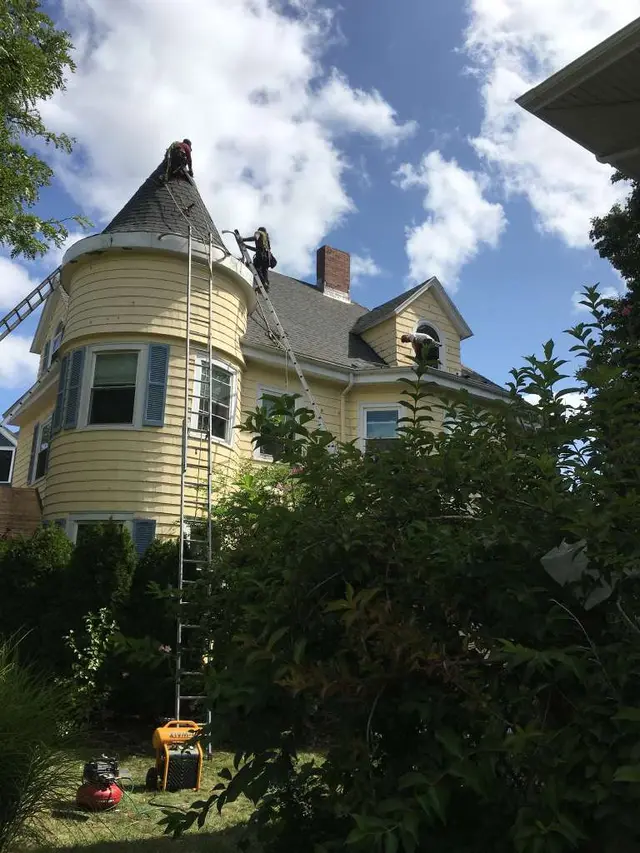 FJM Construction crew repairing the turret roof of a Victorian home in Lynn, MA