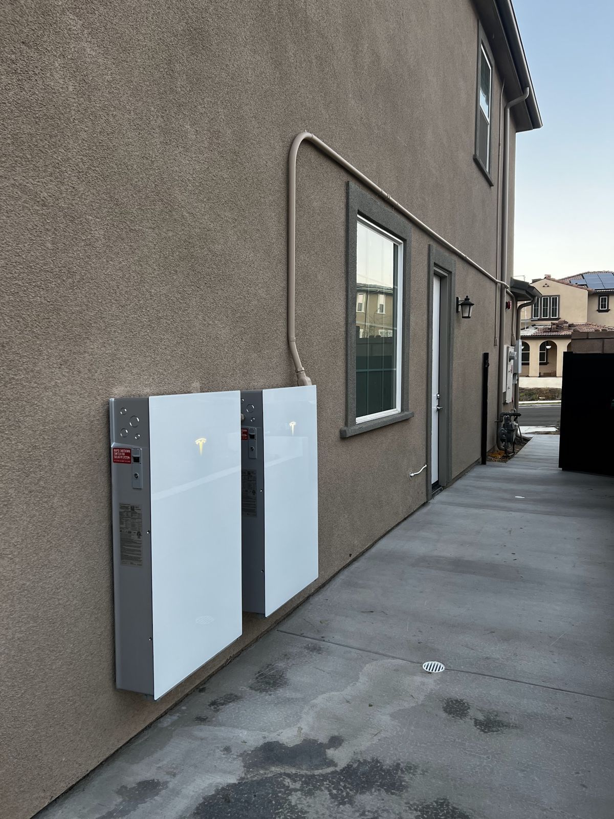Two Tesla Powerwalls on a side yard wall
