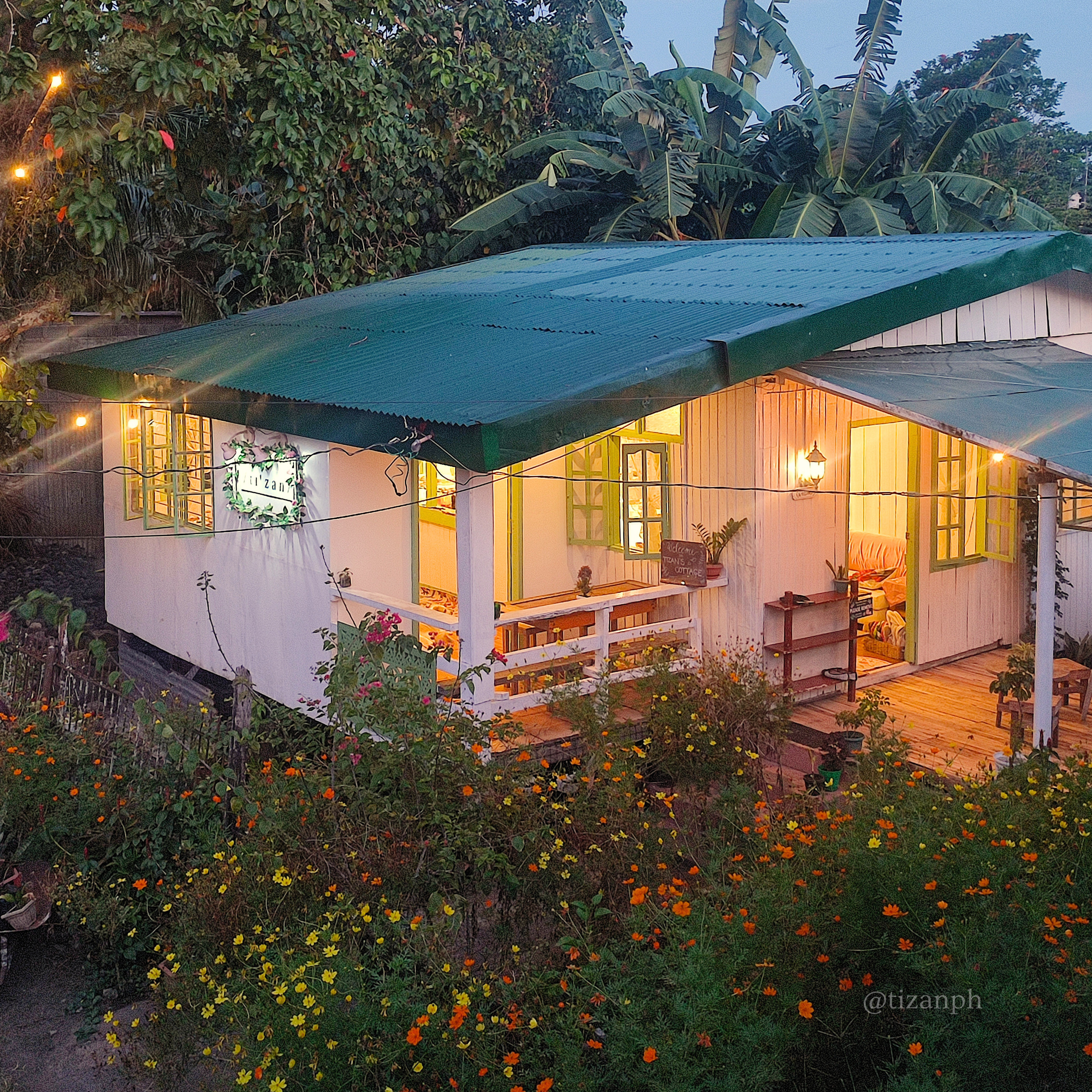 The Tizan cottage tea house glowing among its garden at dusk