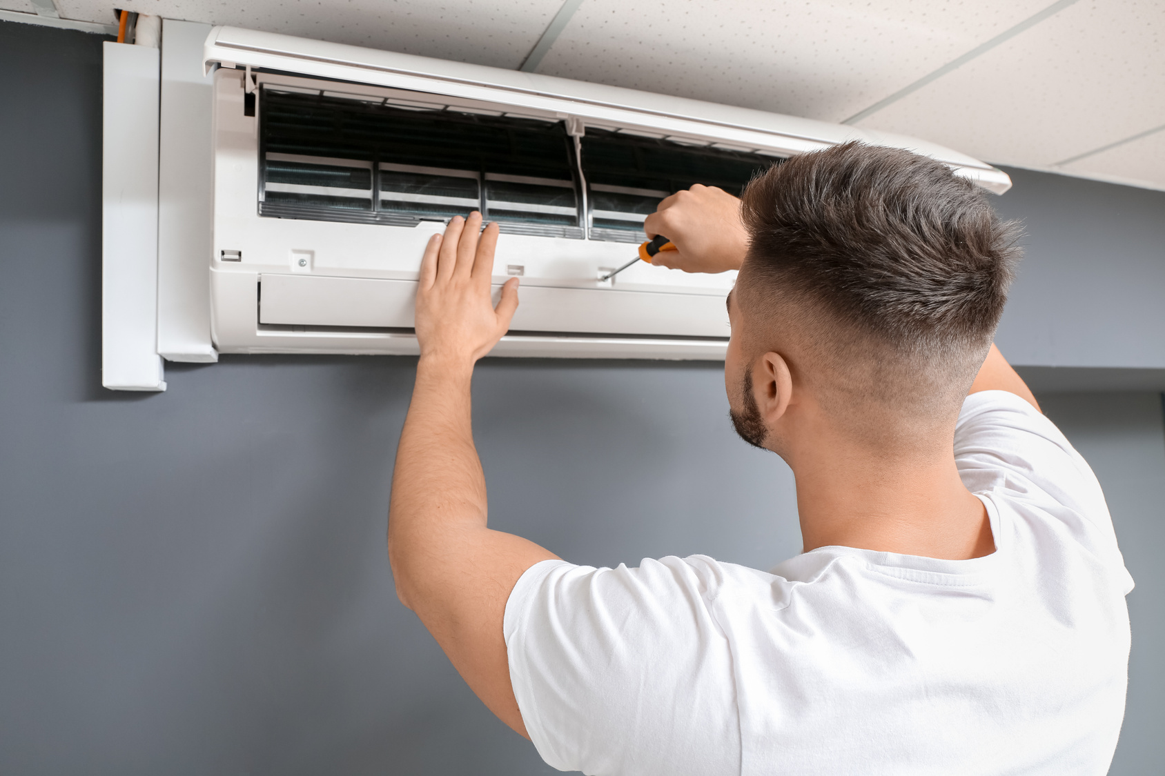 Technician inspecting a wall-mounted air-conditioning unit.