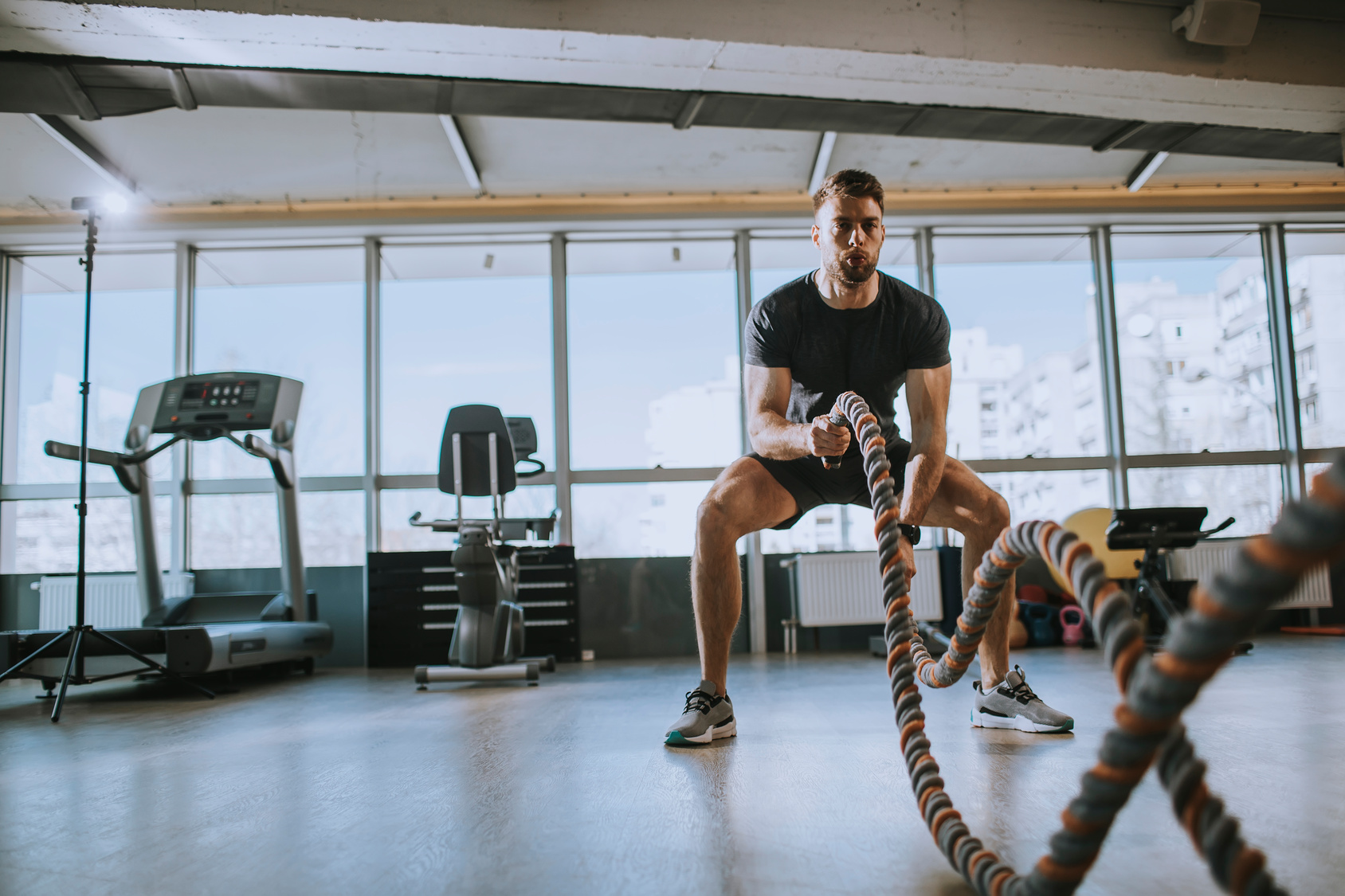 Athlete training with battle ropes in a gym.
