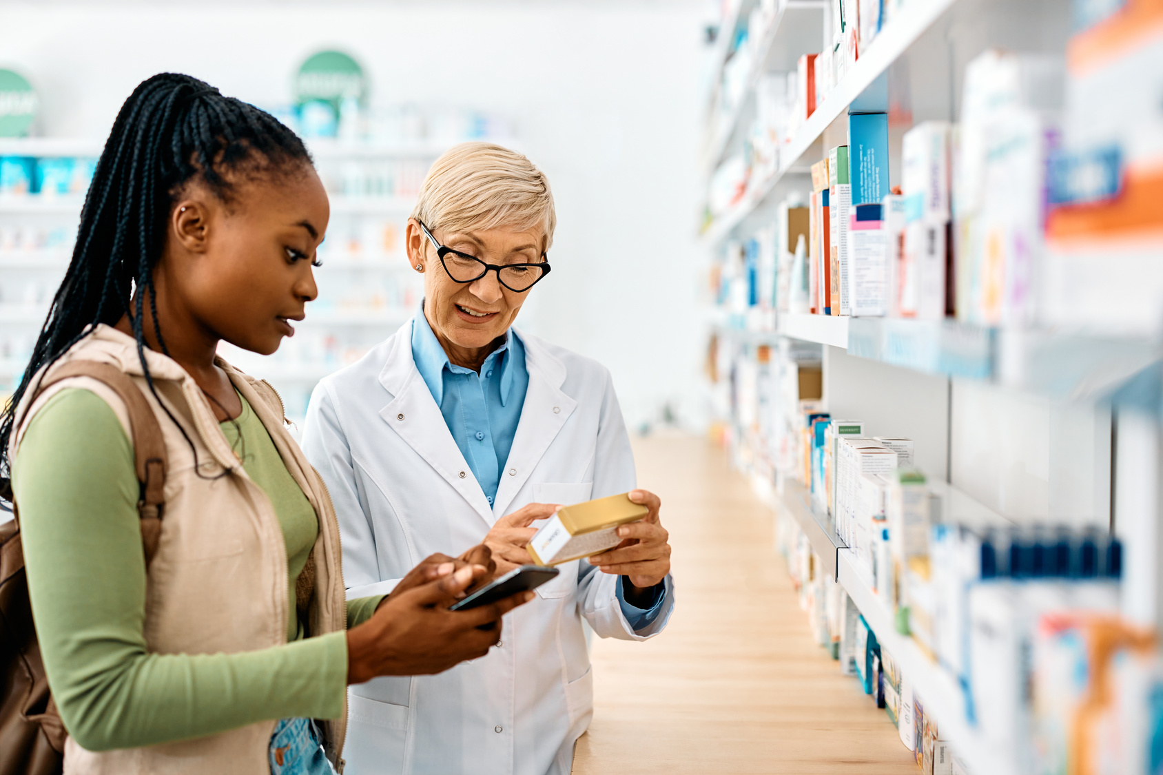 Pharmacist speaking with a customer at a pharmacy counter.
