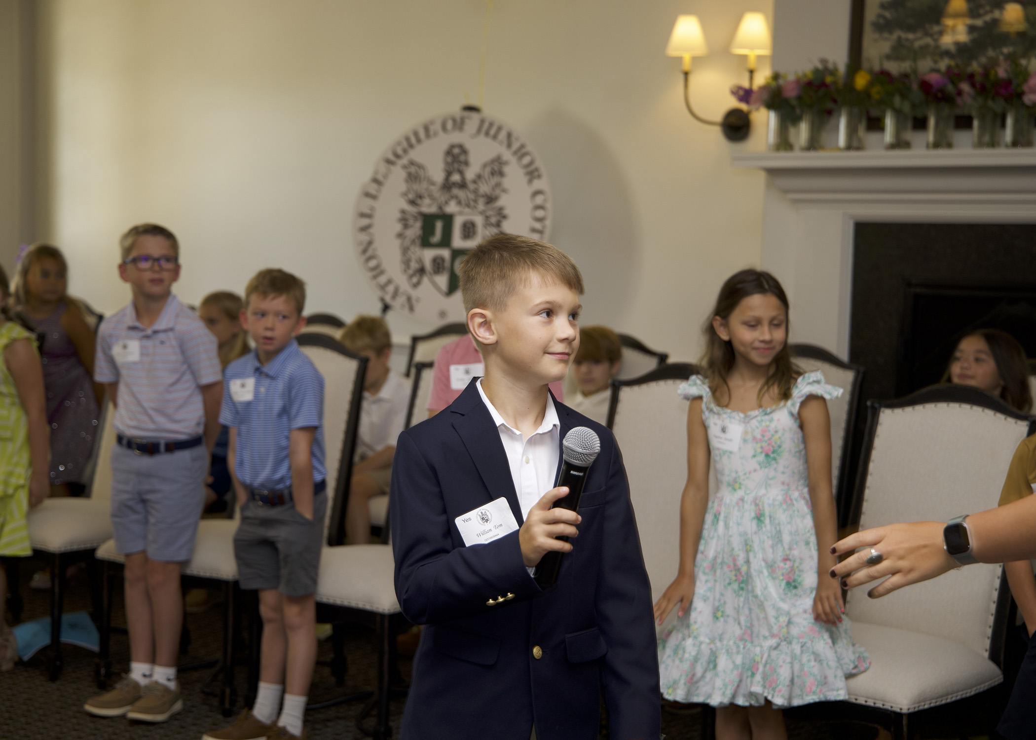 Young gentlemen confidently and happily speaking in front of a group of parents about proper etiquette and good manners.