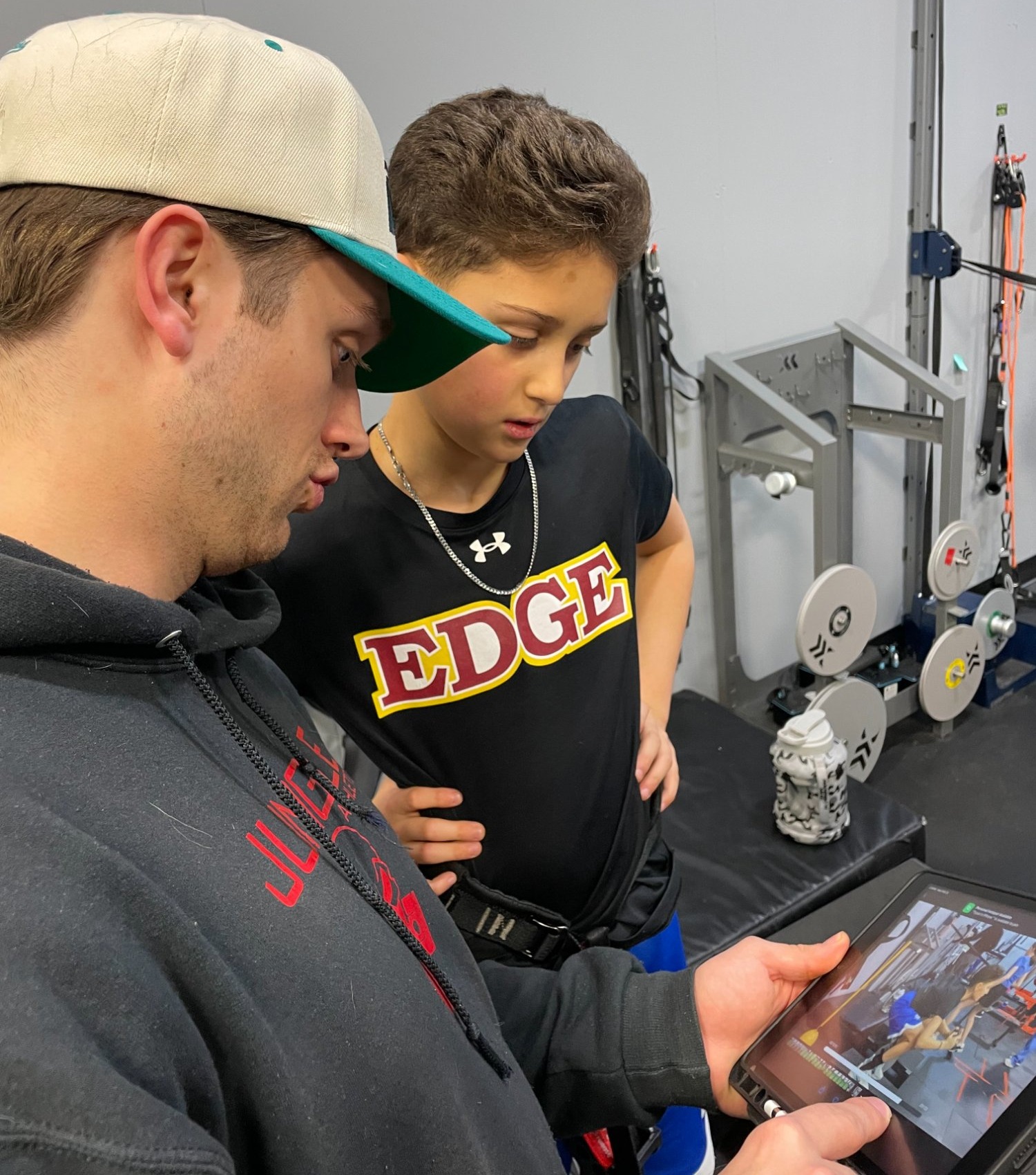 Jungle Athletics coach reviewing video footage with young athlete on tablet