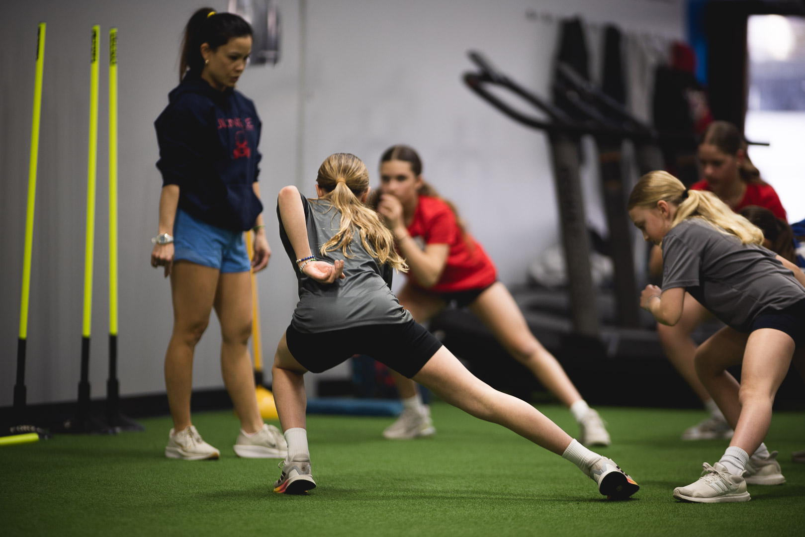 Coach observing SAP group session at Jungle Athletics Calgary — athletes working through skating position drills