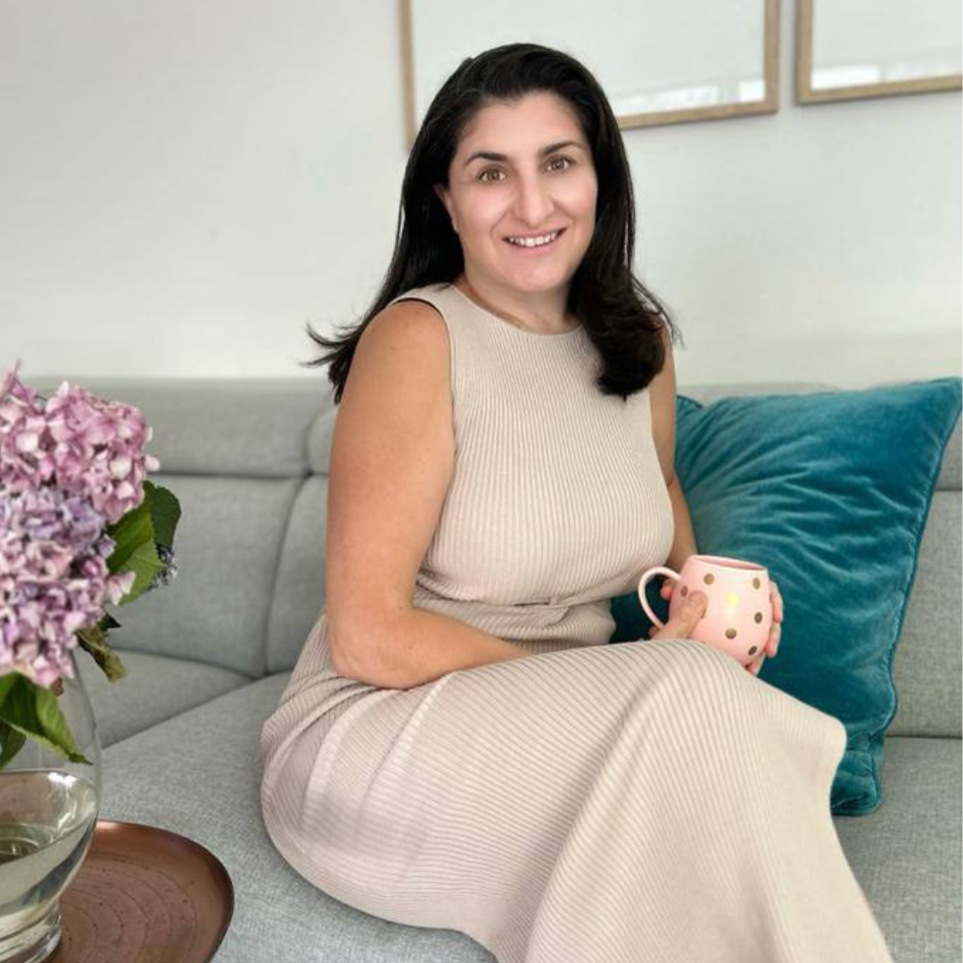 Anil Mustafa sitting on a grey couch holding a mug