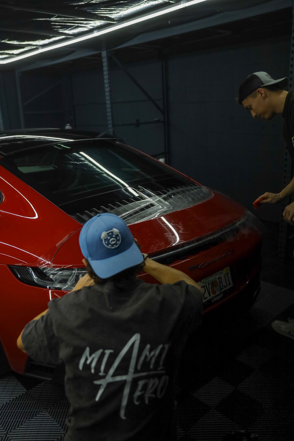 Installers laying film on a rear quarter panel