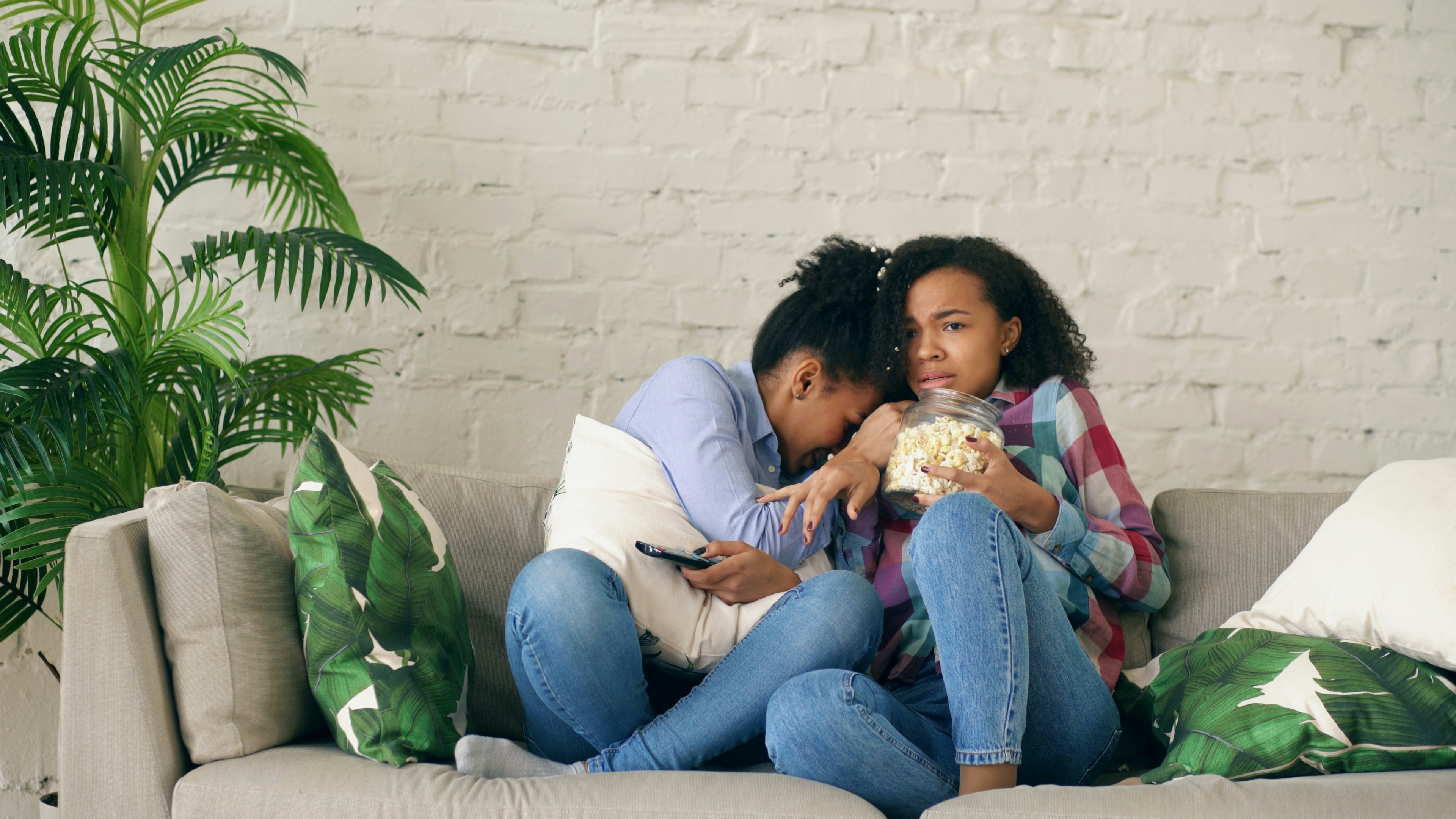 Mother hugging and comforting her upset daughter on the living room sofa Mother hugging and comforting her upset daughter on the living room sofa
