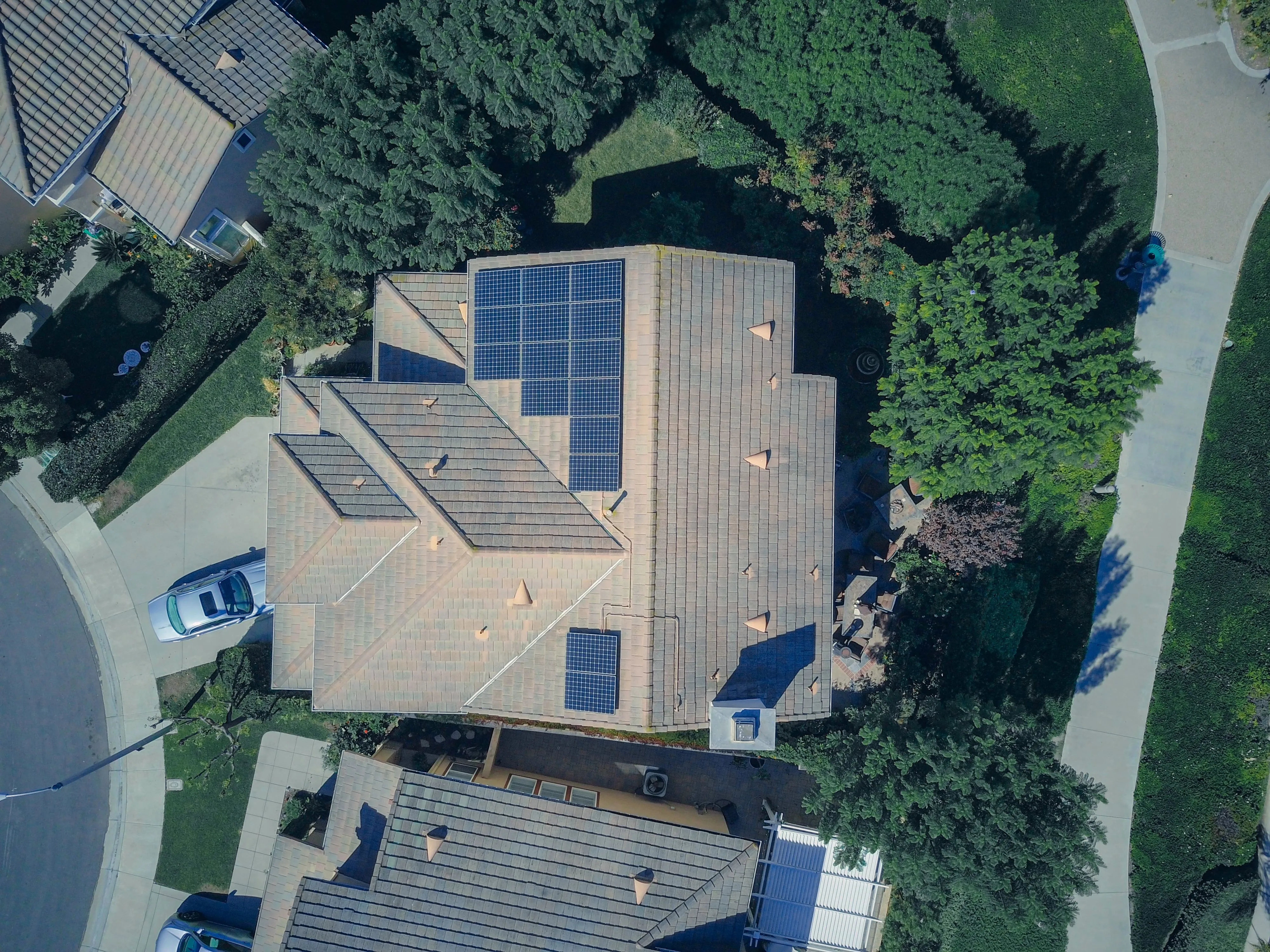 Aerial view of a home with rooftop solar surrounded by trees