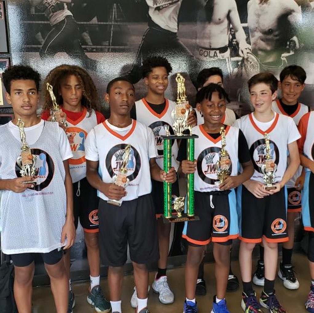 Coach B. Law leading a group basketball training session, demonstrating drills on court