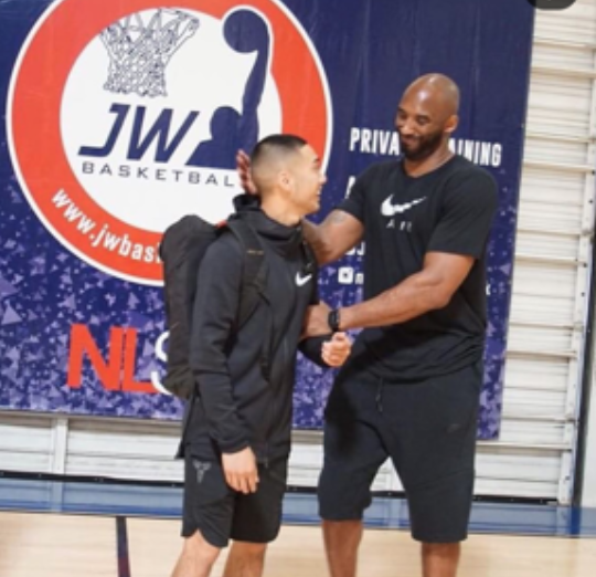 Coach B. Law standing with a group of young basketball players after training session
