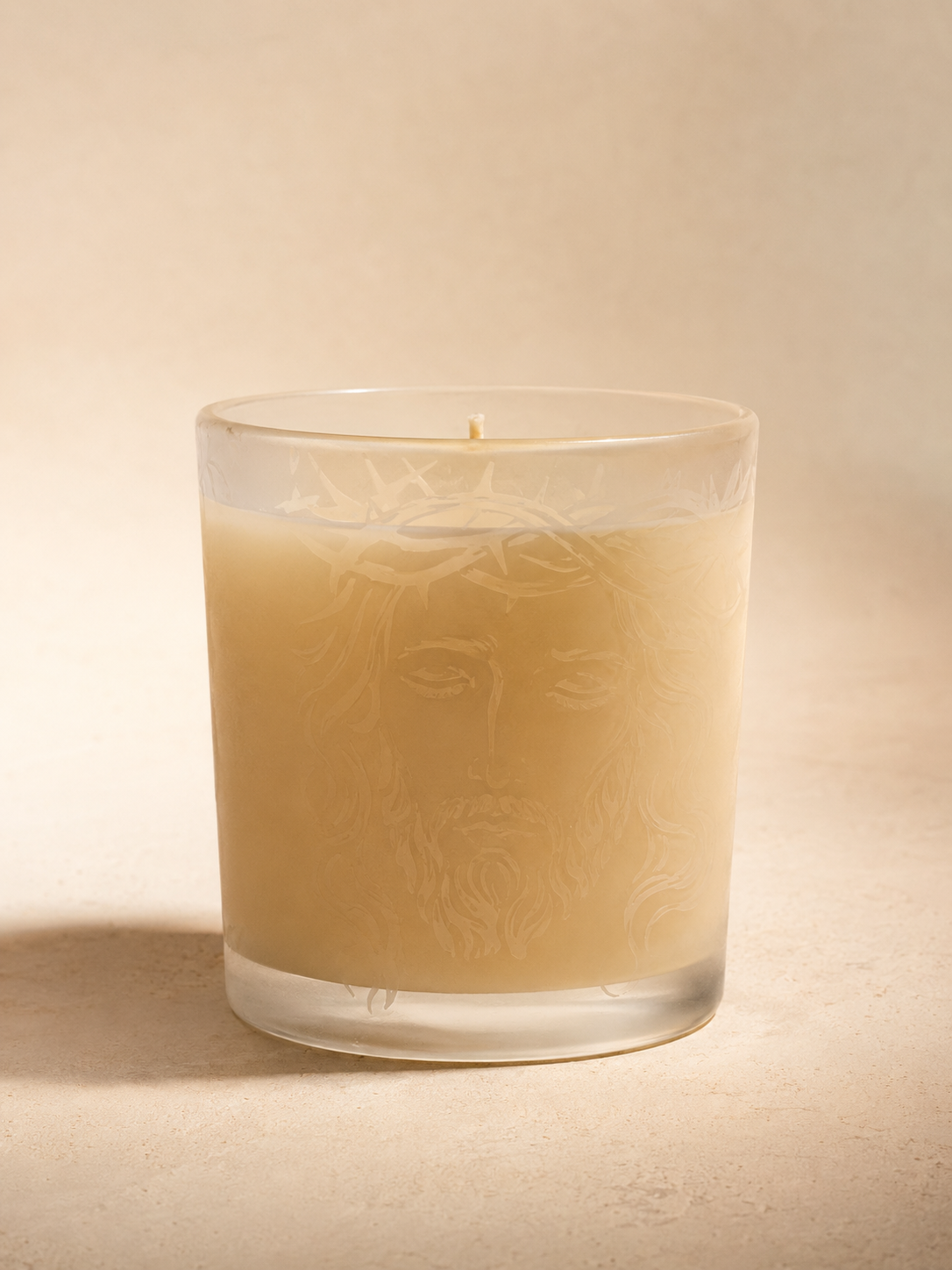 The Casa Selah Prayer Candle: cream wax in a frosted glass vessel etched with the face of Christ crowned in thorns.