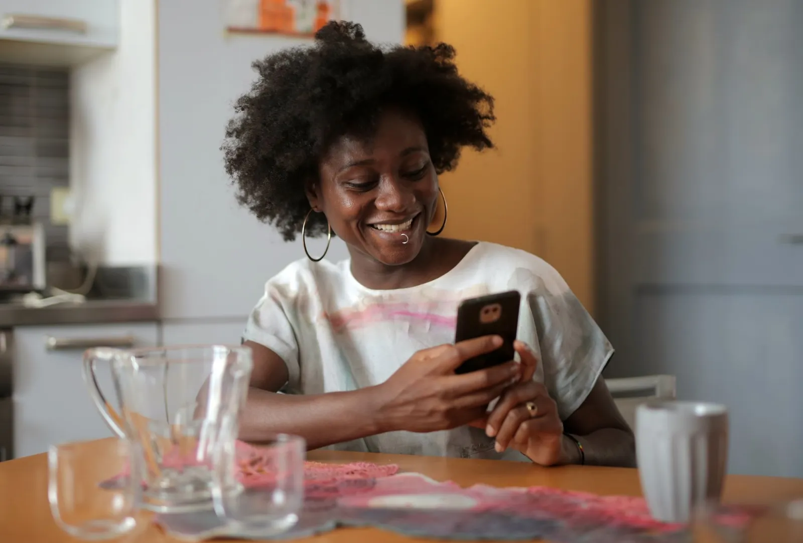 A woman smiling at her phone at a café table