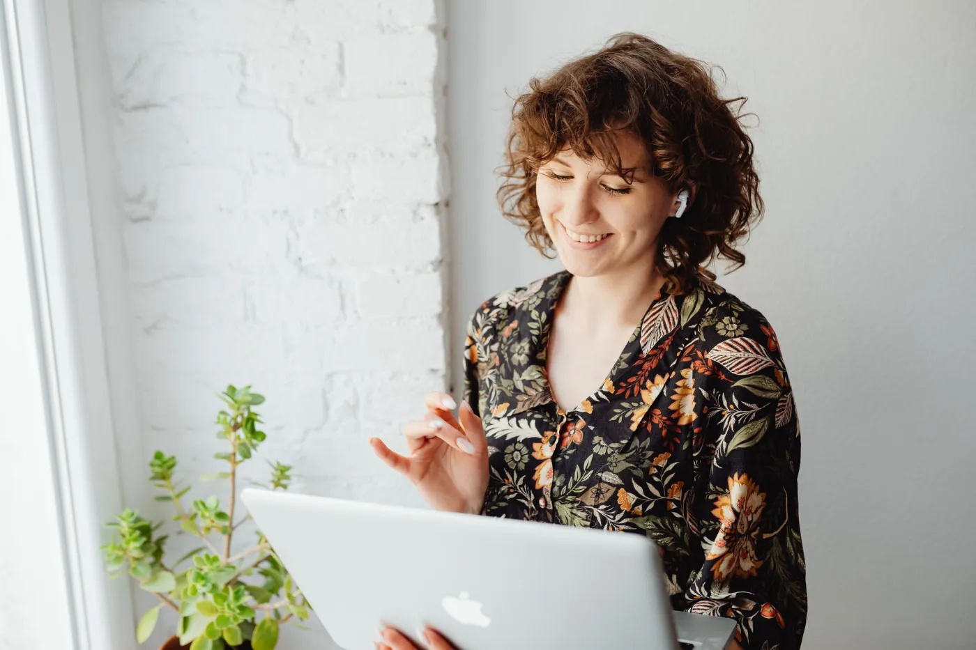 A smiling woman on a video call at her laptop