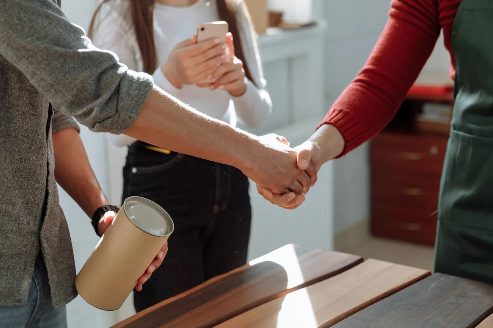 A shop owner shaking hands with a customer