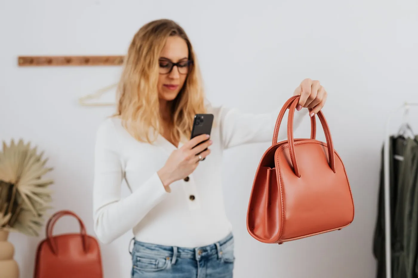 A shop owner photographing a handbag with her phone for social media