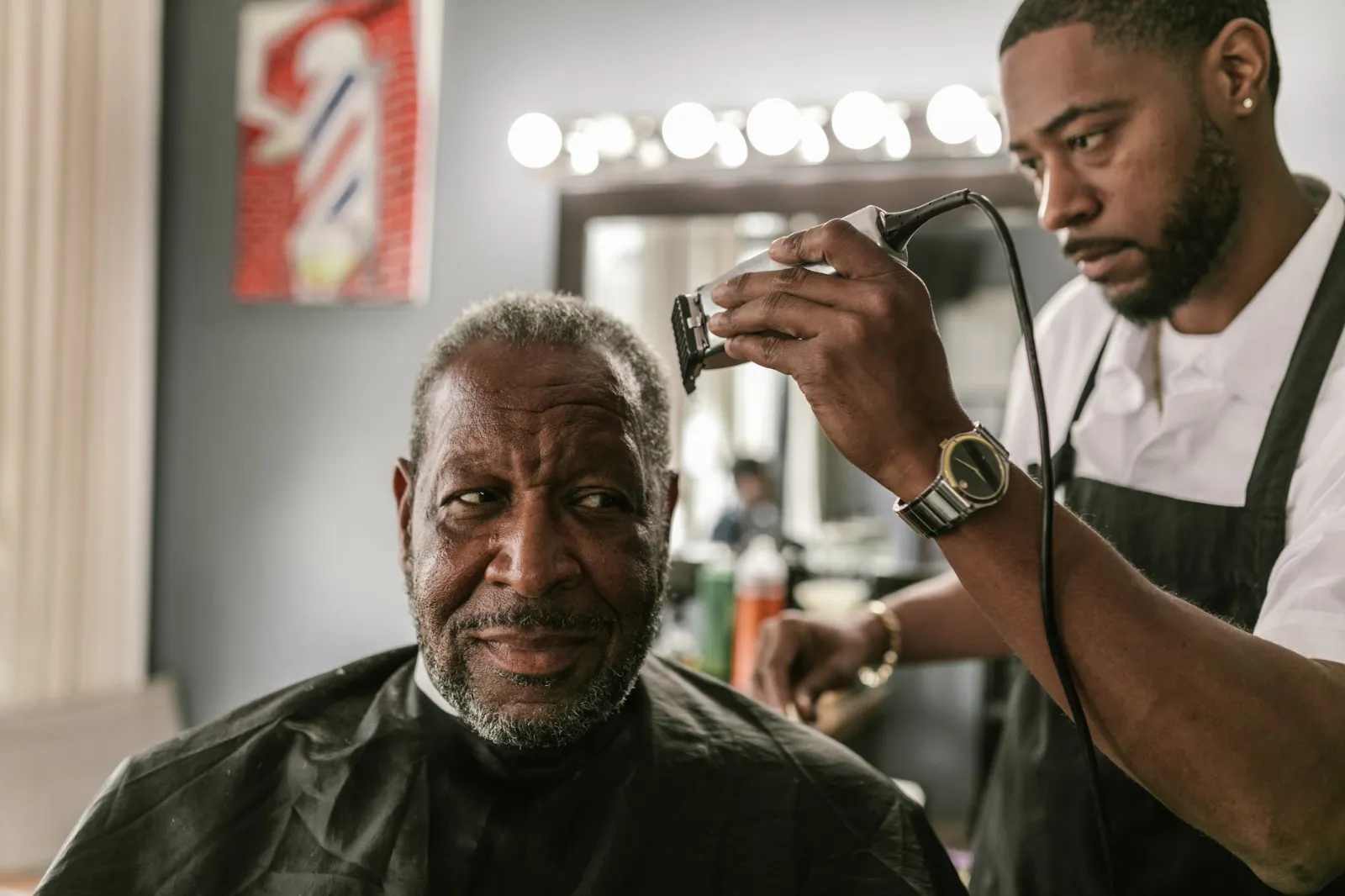 A barber trimming a smiling client's hair