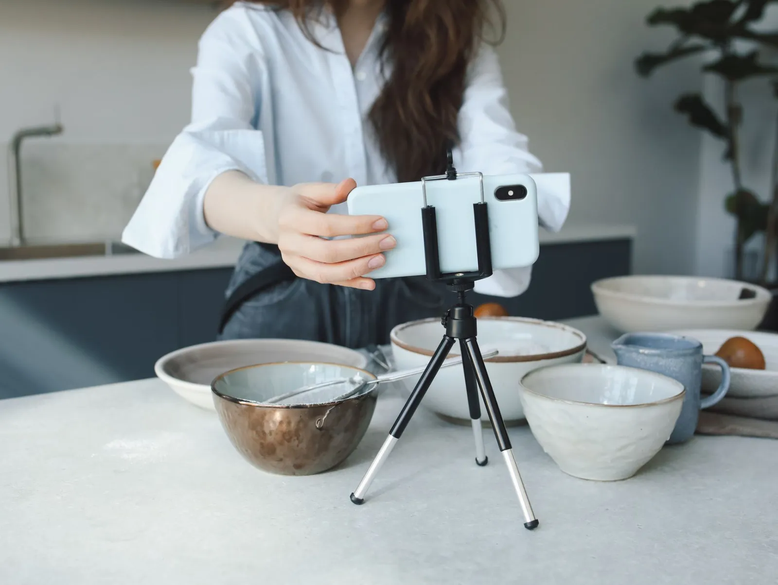 A phone on a small tripod filming bowls on a counter
