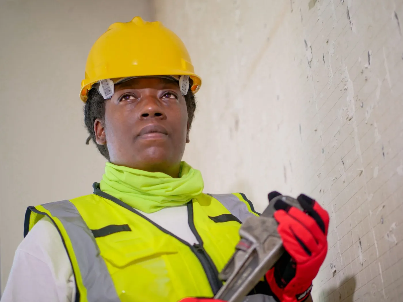 A tradesperson in a hard hat and safety vest at work