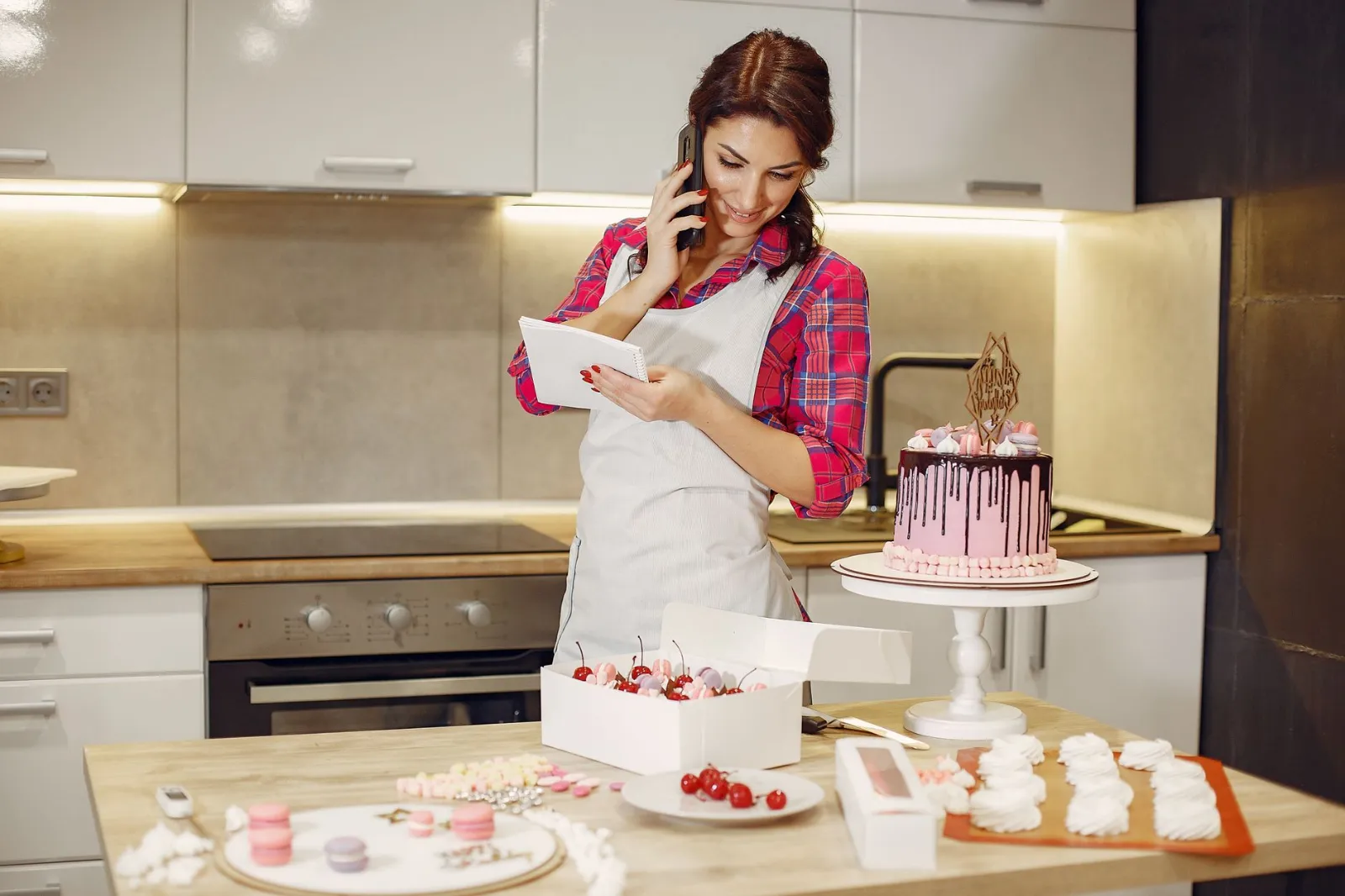 A baker answering the phone while taking an order in her kitchen