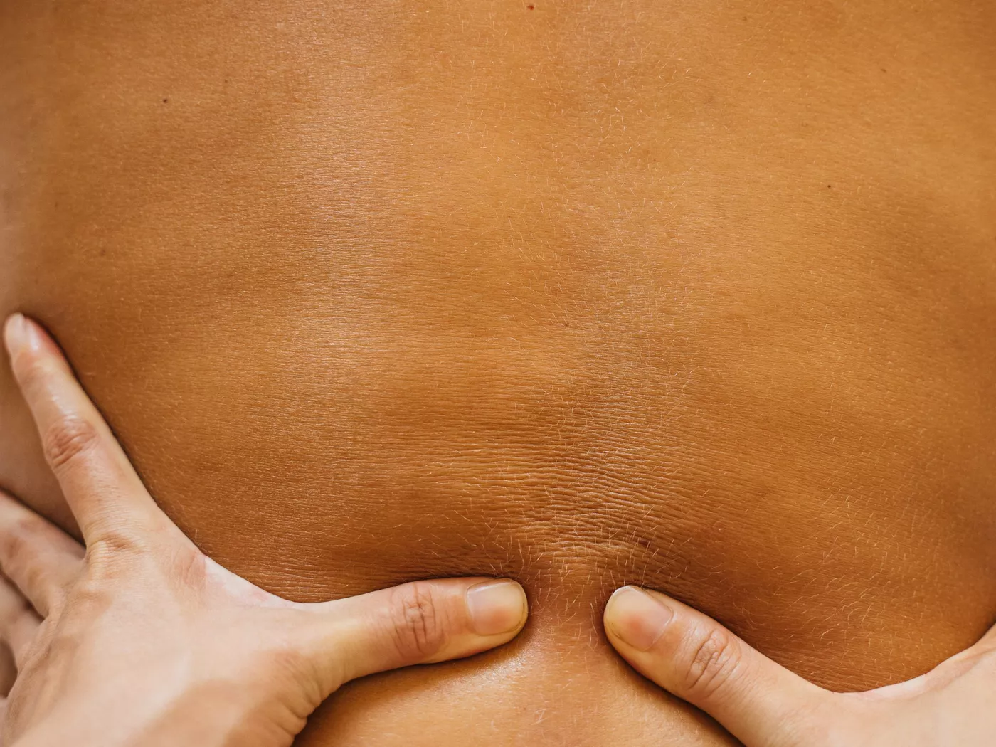 A massage therapist's hands working on a client's back