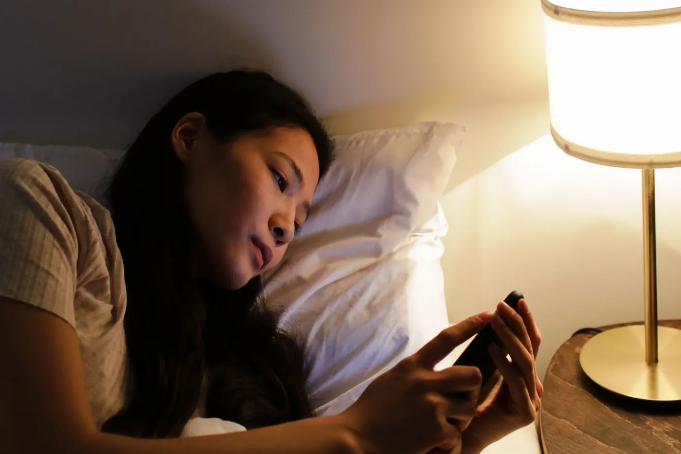 An owner answering messages on her phone in bed late at night