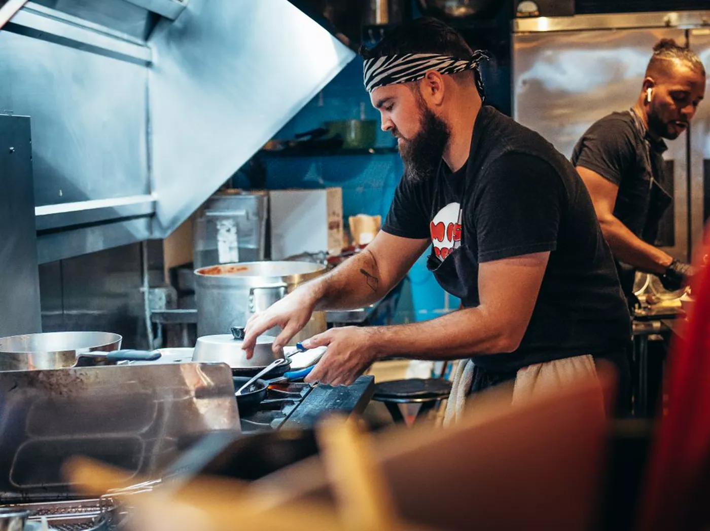 Two chefs work diligently in a bustling restaurant kitchen, preparing meals and managing dishes.