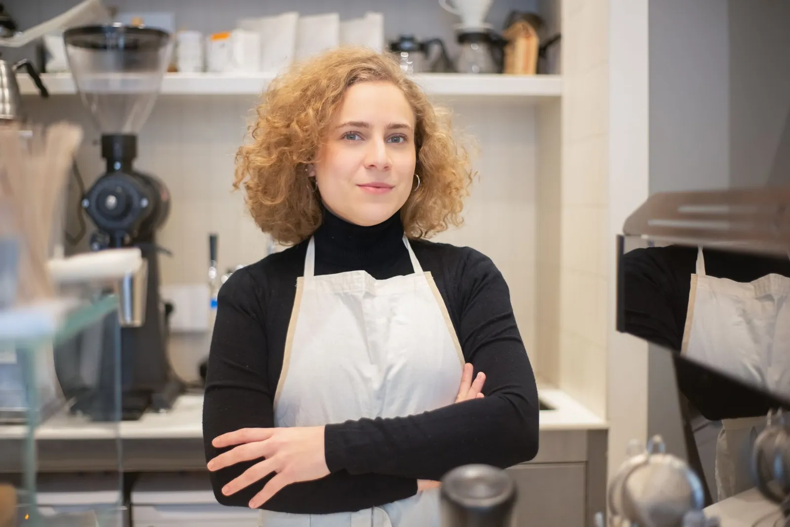 A calm café owner standing with her arms crossed