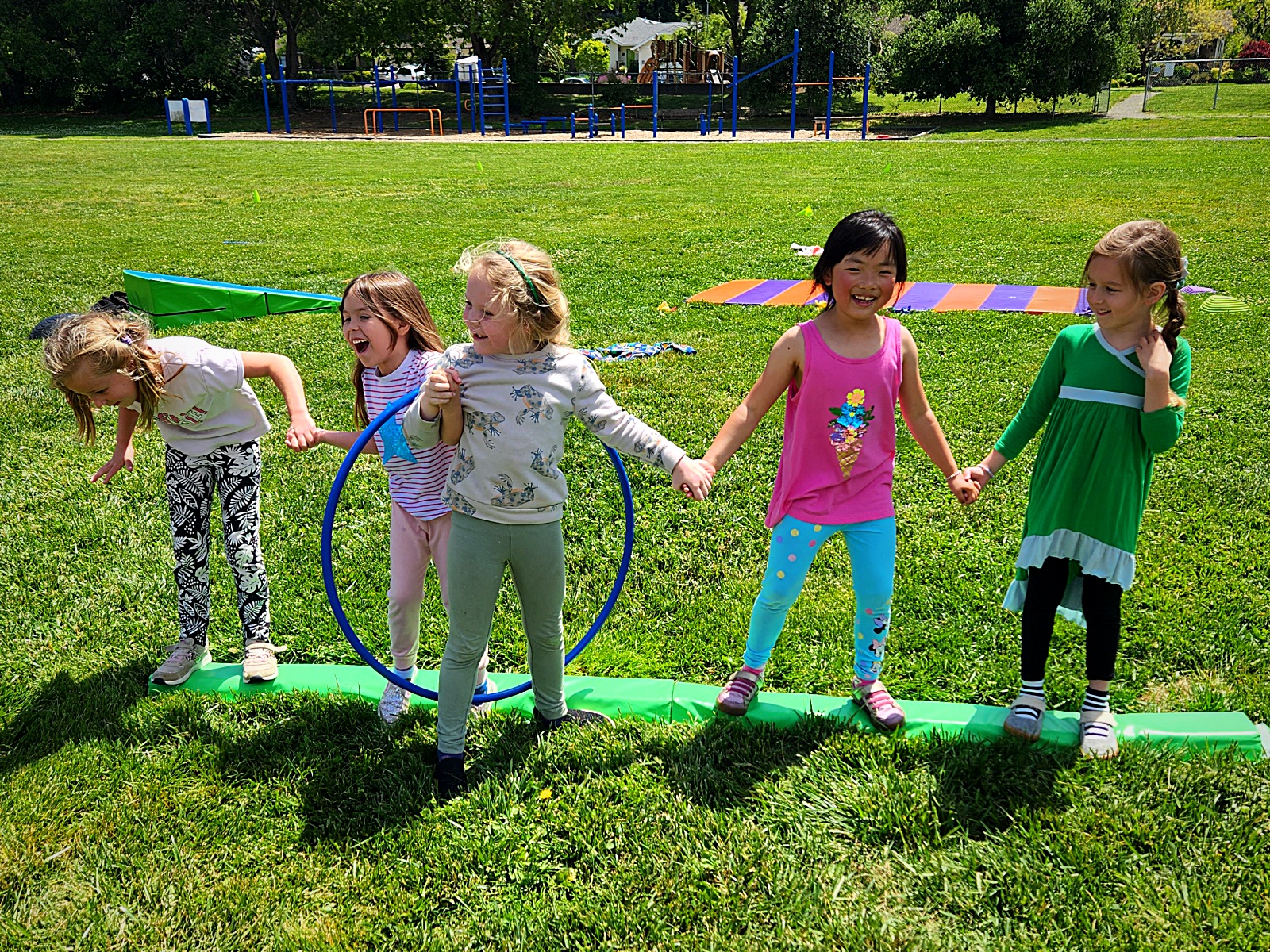 Campers balancing on a beam with a hula hoop